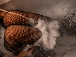 knee of woman wearing mesh stockings inside bathtub with water